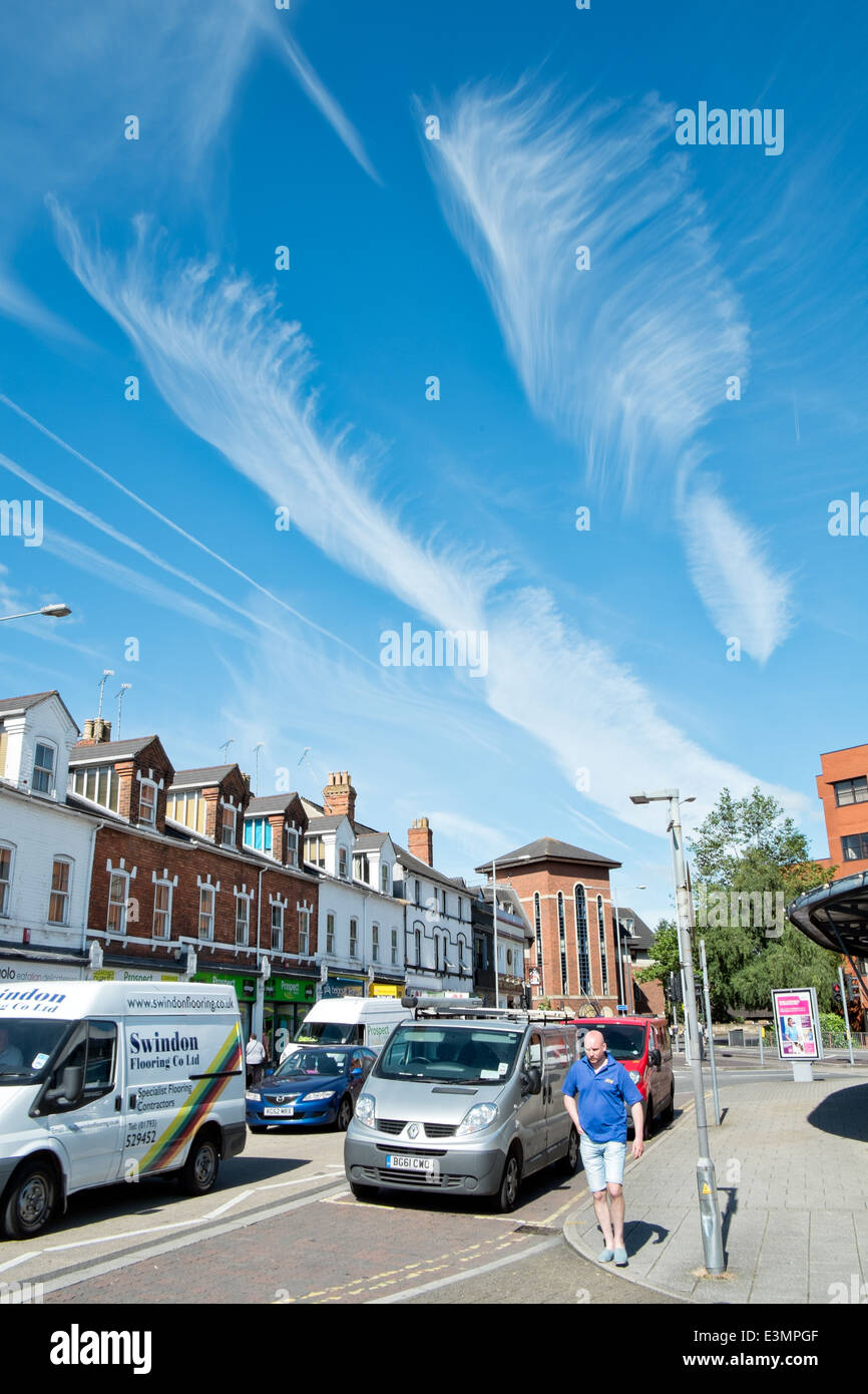 Come piume cirrus formazioni di nubi in un azzurro cielo estivo al di sopra di un tipico British scene di strada Foto Stock