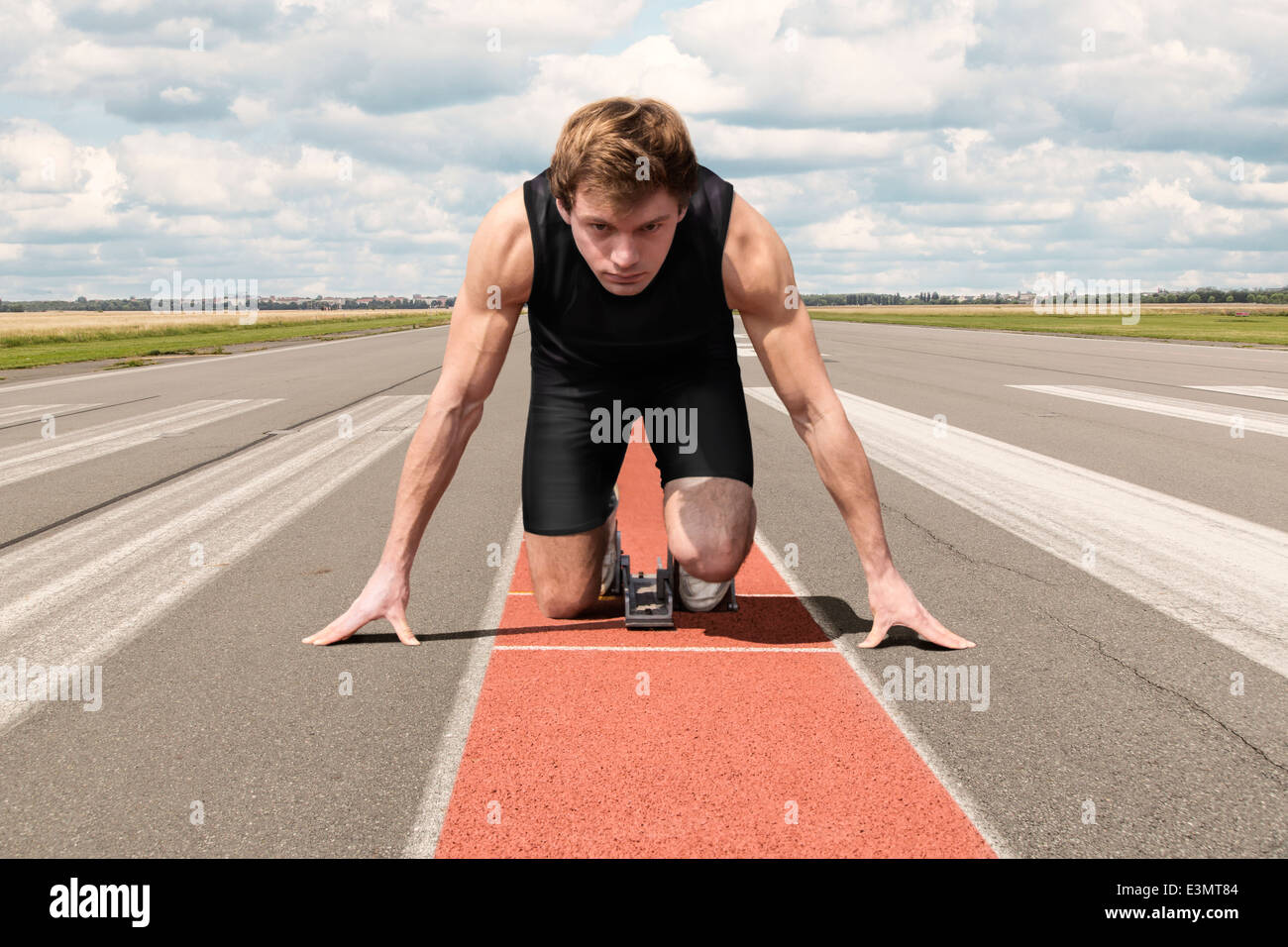 Atleta maschio sulla pista di aeroporto preparando per il suo inizio Foto Stock