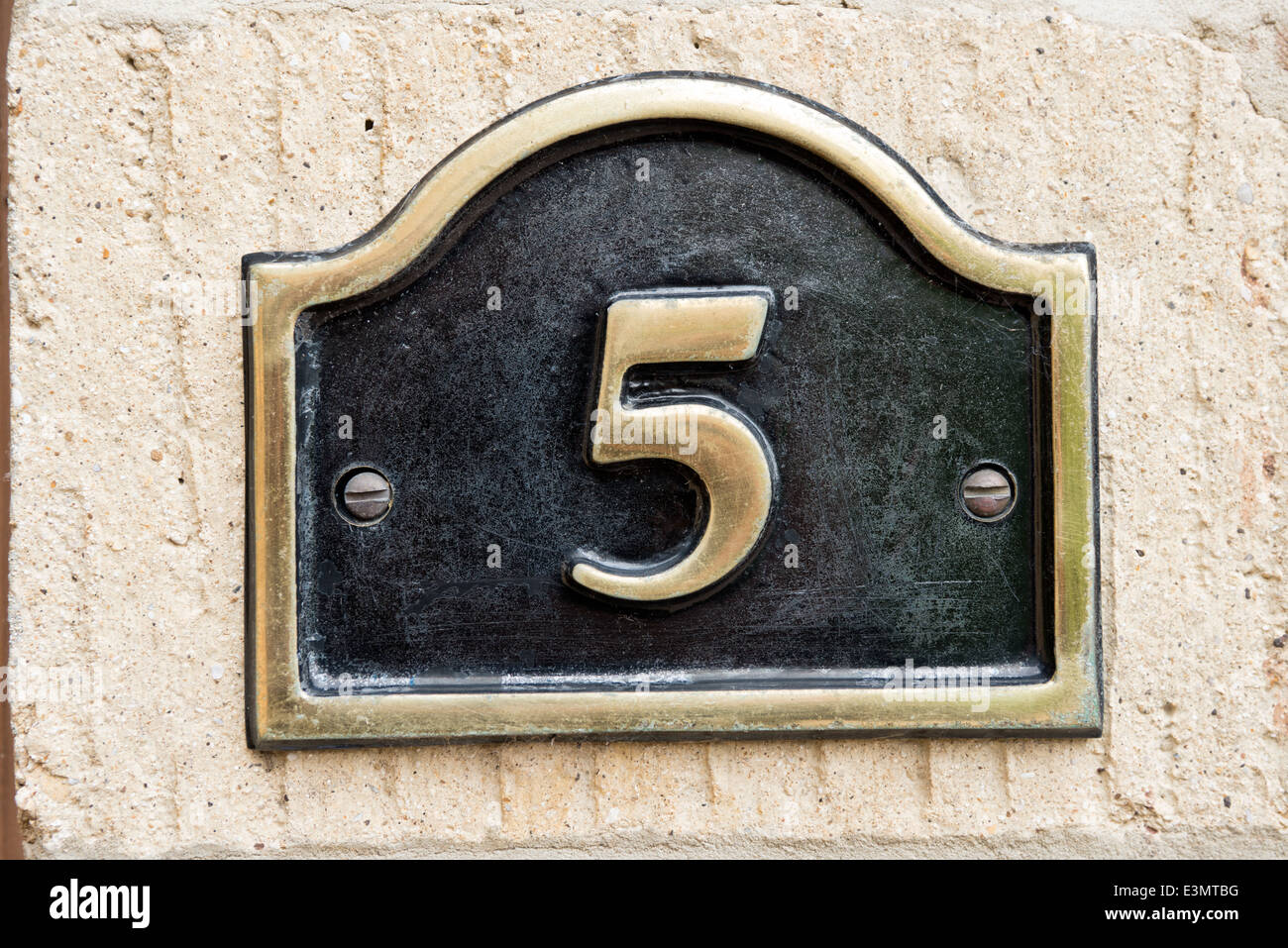 Una targa in ottone con la visualizzazione del numero 5 montato su una parete di una casa identificare le case indirizzo Foto Stock