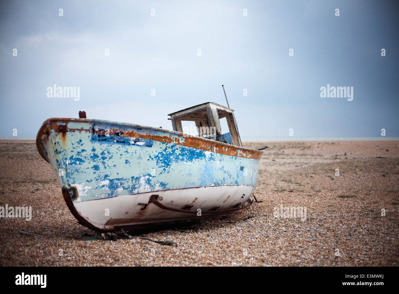 Elica in legno vecchie barche da pesca a sinistra sulla spiaggia a decadimento su una deserta spiaggia ghiaiosa Foto Stock