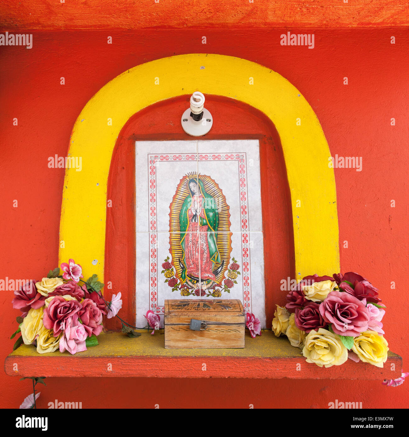 Una immagine della Vergine di Guadalupe contro una parete arancione in Acayucan, Veracruz, Messico. Foto Stock