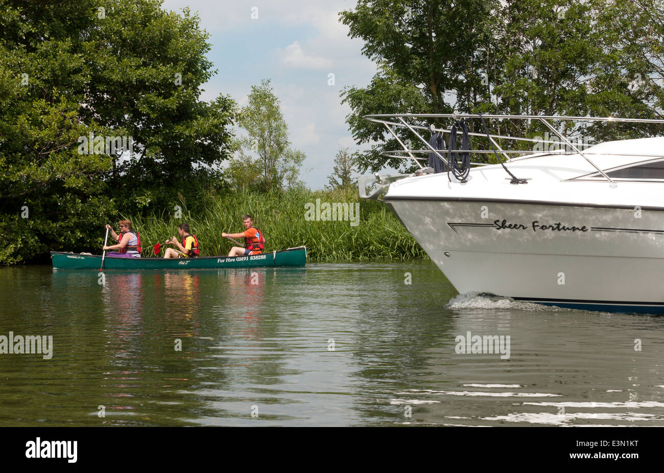 Una canoa rischia di essere superato da una barca a motore sul fiume Tamigi, Oxfordshire, Regno Unito Foto Stock