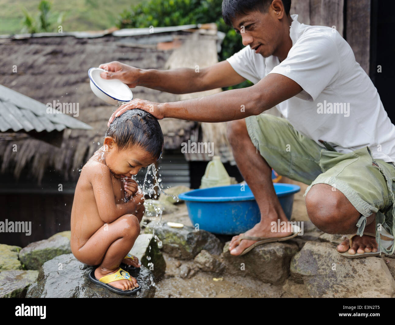 L'uomo la balneazione il suo figlio in strada, Tinglayan, Filippine Foto Stock
