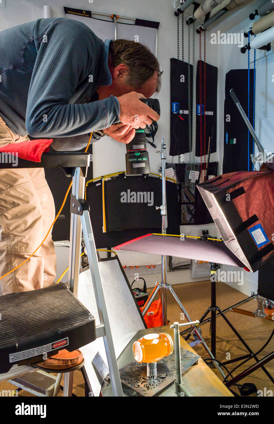 Un fotografo professionista che lavora in una fotografia commerciale studio, compresi illuminazione, sfondo e ingranaggio di presa. Foto Stock