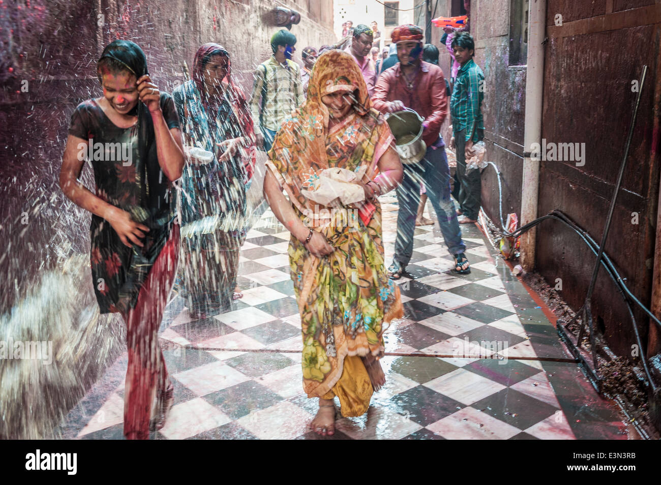 Donne imbevuto di acqua colorata durante le celebrazioni di holi festival, Vrindavan, India Foto Stock