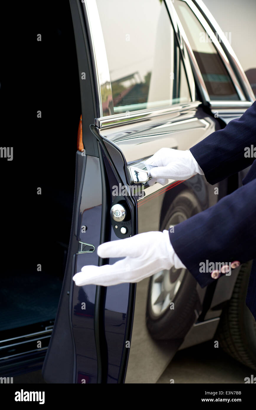 Autista auto apre la porta di una Rolls Royce Foto Stock
