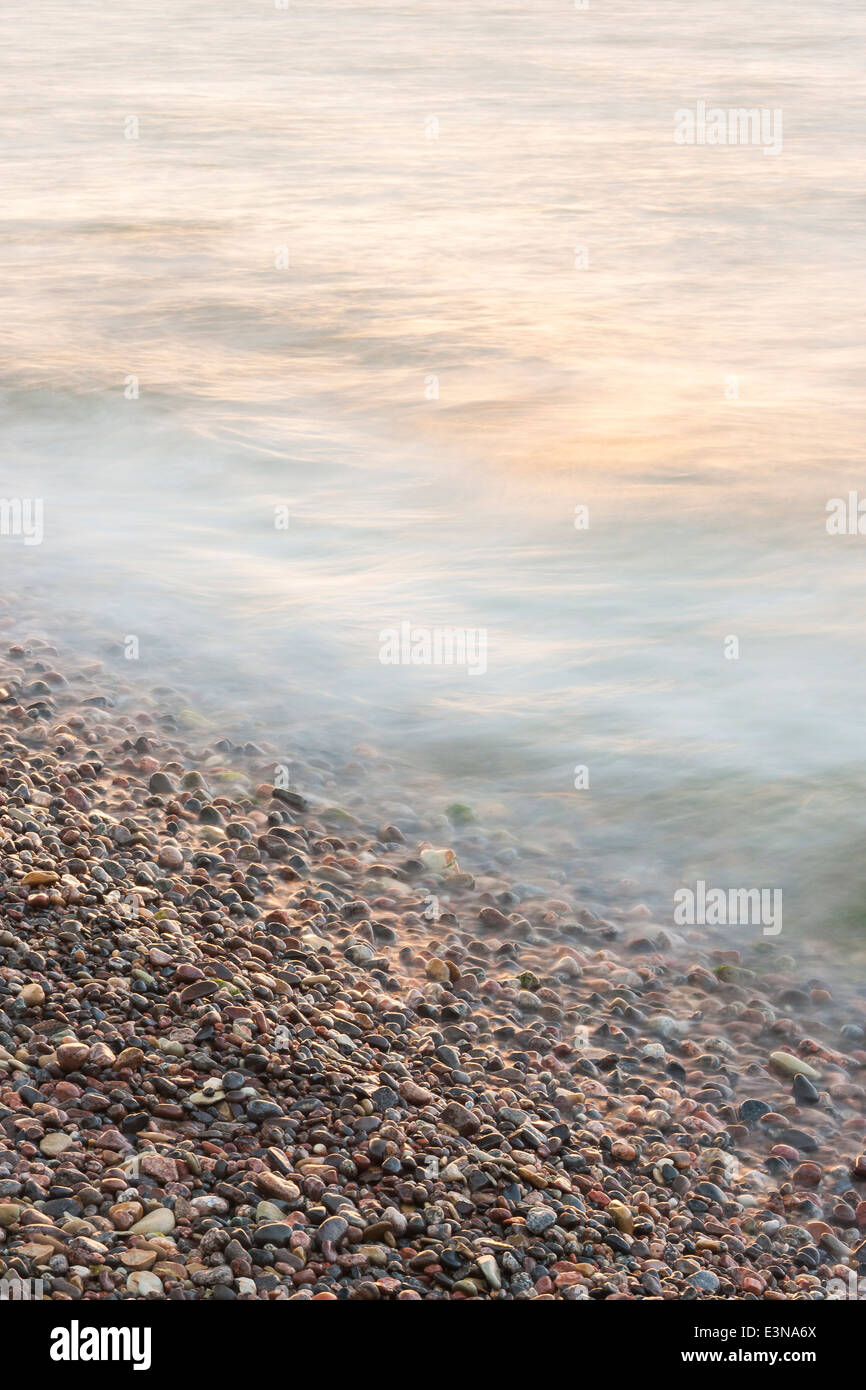Onde di acqua su piccola round sassi o pietre in una spiaggia Foto Stock