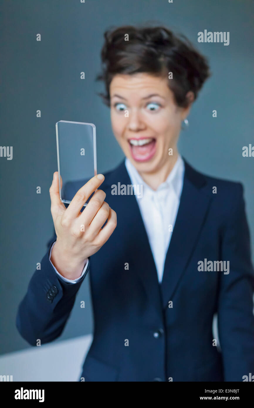 Imprenditrice estatica Guardando Blank futuristico Smartphone trasparente Foto Stock