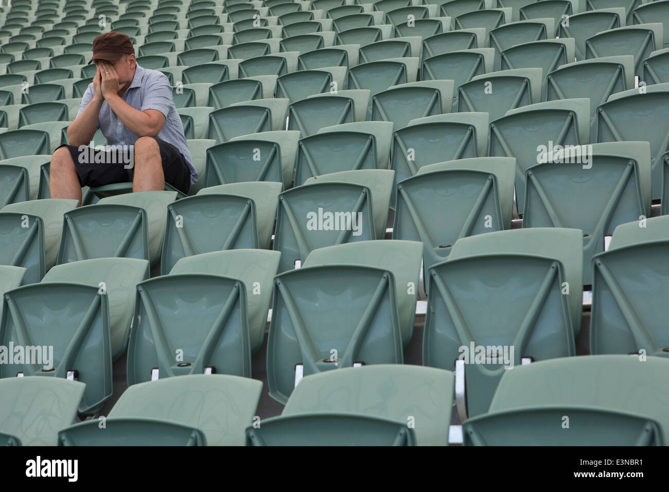 Triste uomo seduto da solo in stadio vuoto Foto Stock