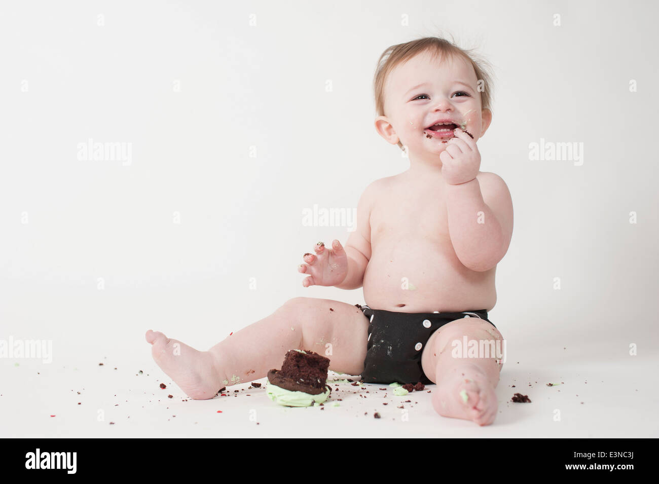 Lunghezza completa di simpatici baby boy mangiare cupcake contro uno sfondo bianco Foto Stock