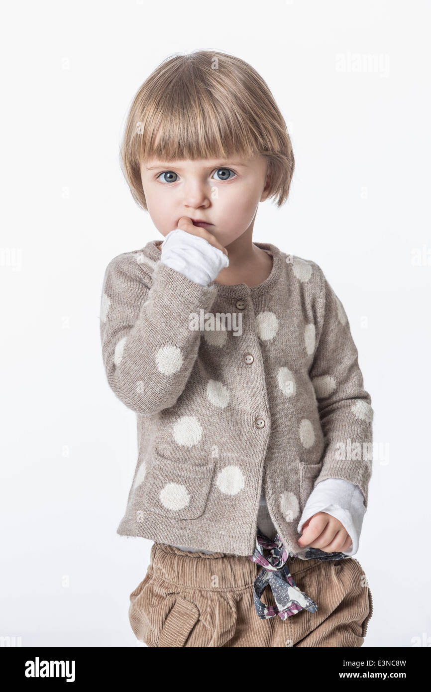 Ritratto di ragazza carina con il dito in bocca contro uno sfondo bianco Foto Stock