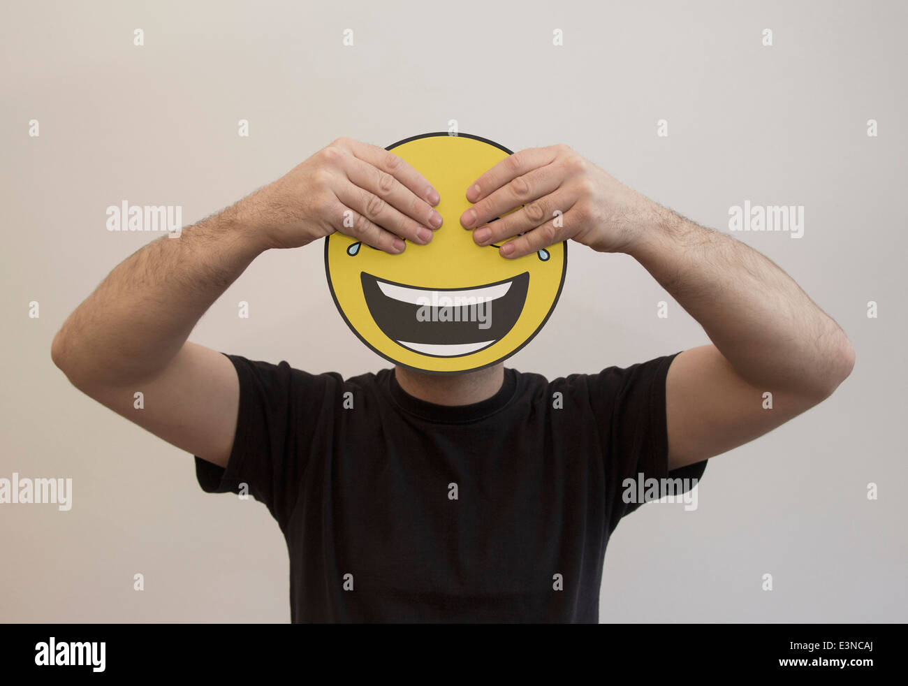 Uomo che tiene con le mani che coprono gli occhi di un emoticon felice faccia Foto Stock
