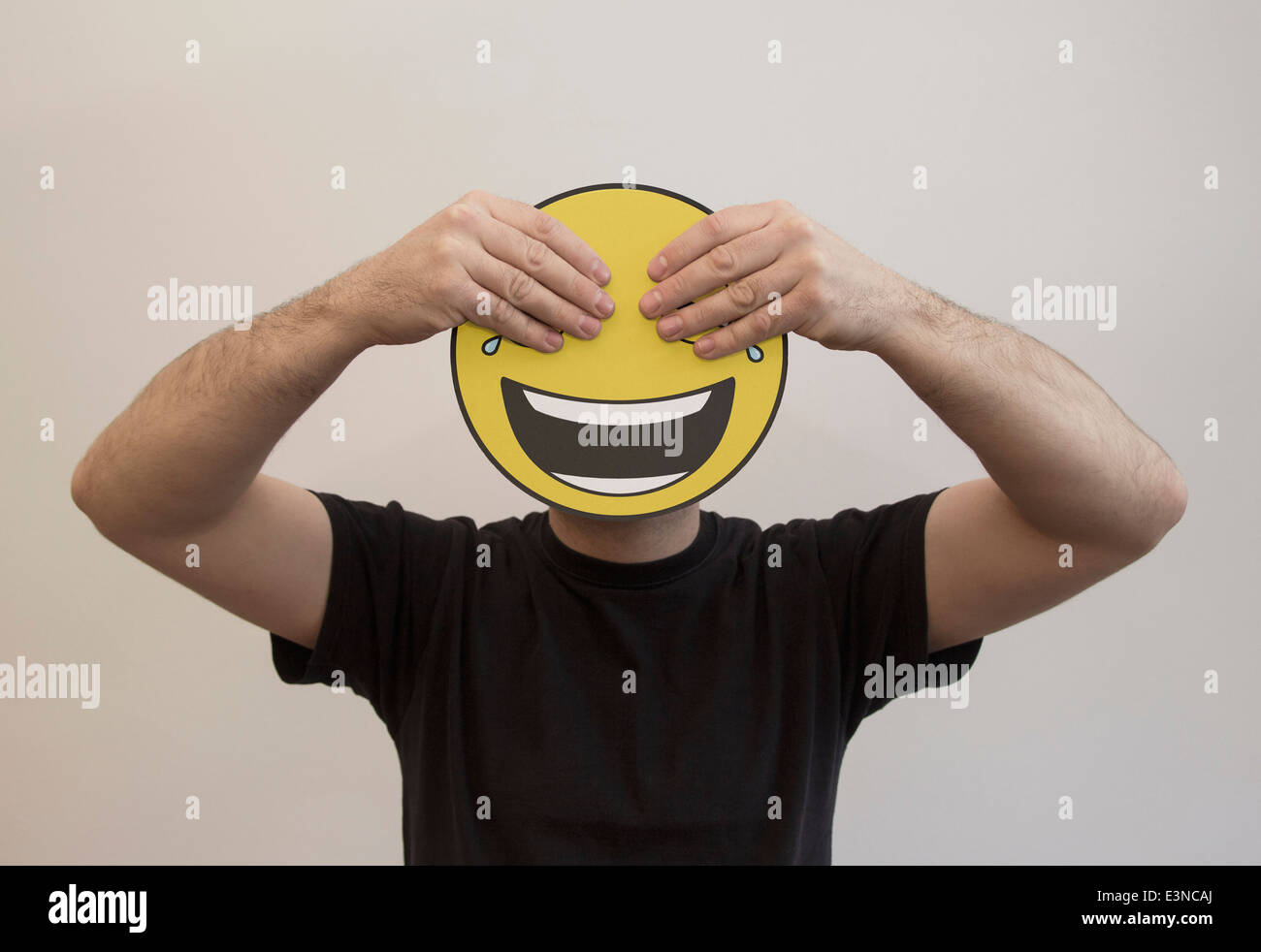 Uomo che tiene con le mani che coprono gli occhi di un emoticon felice faccia Foto Stock Uomo che tiene con le mani che coprono gli occhi di un emoticon felice faccia Foto Stock