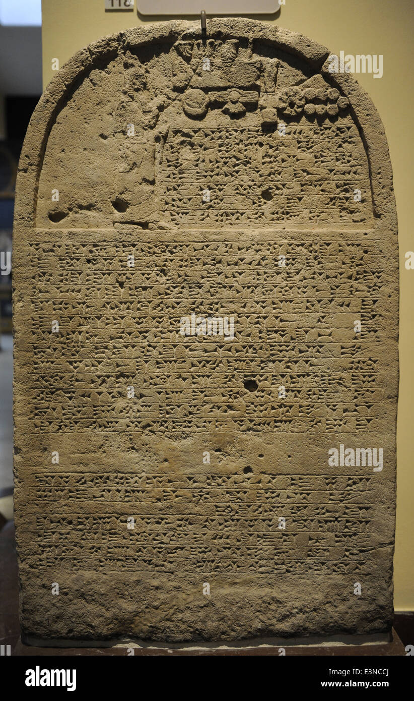 Re della stele con iscrizione e un rilievo raffigurante il re Sennacherib pregando davanti del divino i simboli. Calcare. Foto Stock