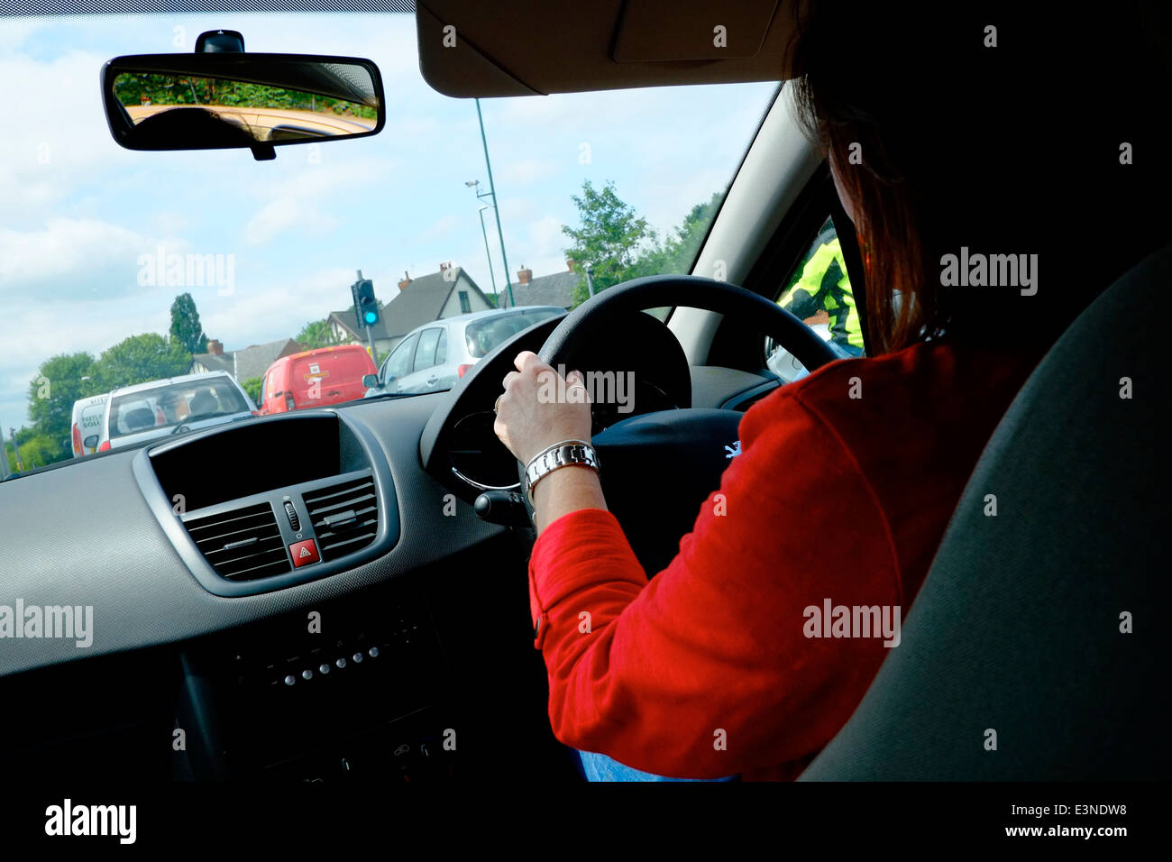 Una femmina di guidare una macchina a motore attraverso traffico England Regno Unito Foto Stock