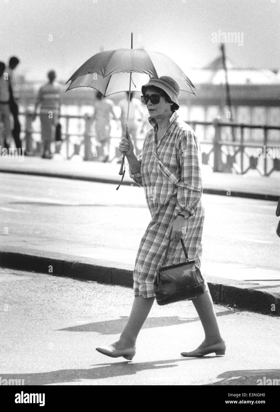 Questa signora rimane in ombra sotto il suo ombrello in un giorno di agosto caldo lungo Brighton Seafront - 1988 Foto Stock