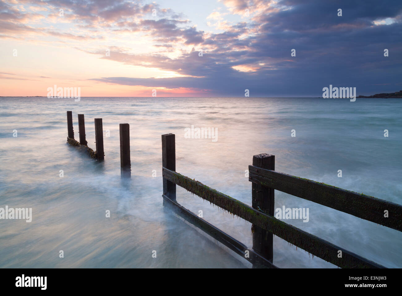 Posti di legno al tramonto Vazon beach l'isola di Guernsey Foto Stock
