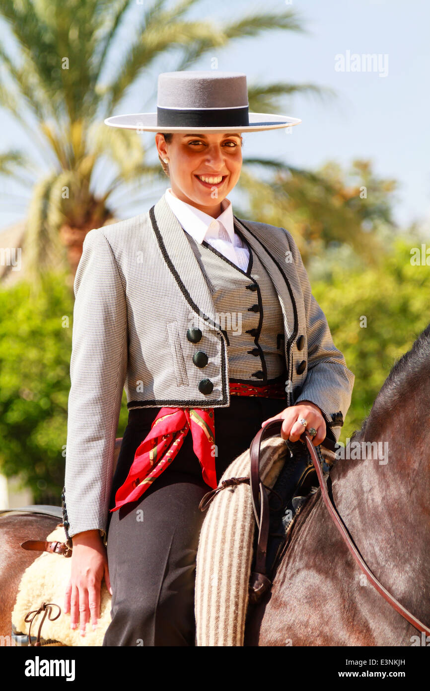 Pilota femmina decked out nel piatto tradizionale-sormontato hat seduta sul suo cavallo sorridente durante la Feria del Caballon. Foto Stock