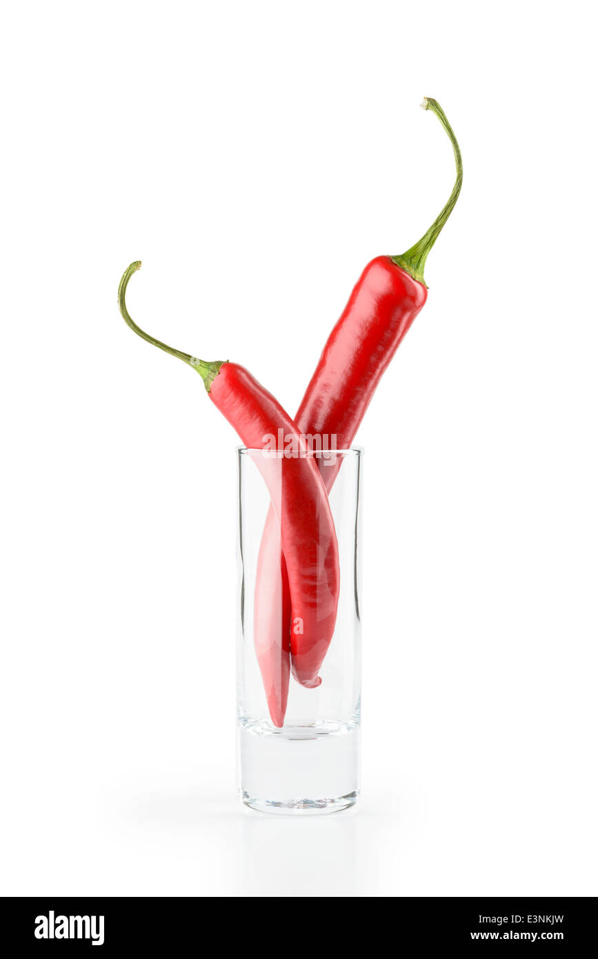 Due red hot chili peppers in un bicchiere di vodka, isolato su sfondo bianco Foto Stock
