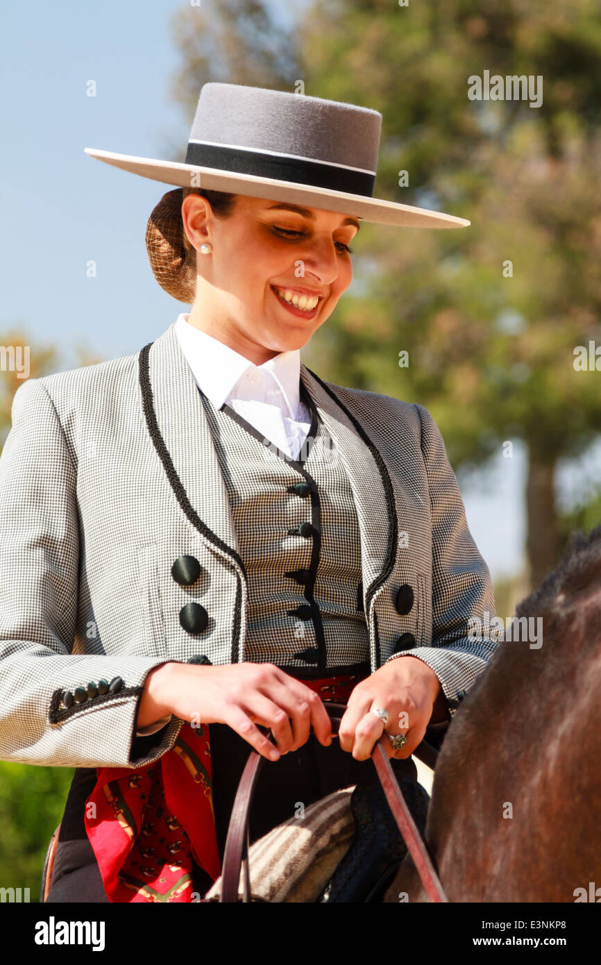Pilota femmina decked out nel piatto tradizionale-sormontato hat seduta sul suo cavallo sorridente durante la Feria del Caballon, Spains fiera cavalli Foto Stock