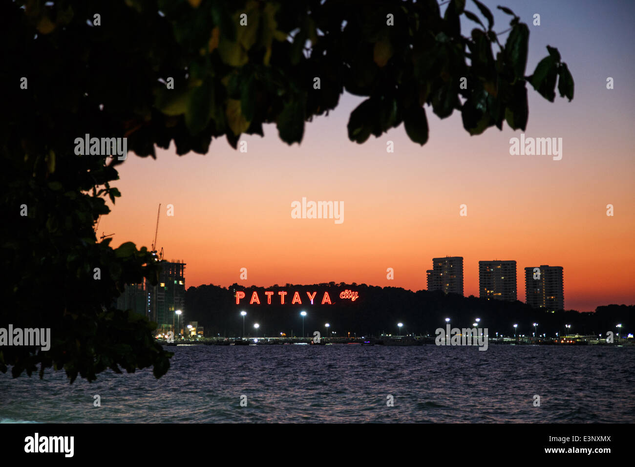 La spiaggia durante il tramonto con il Pattaya insegna al neon in background in Pattaya, Thailandia Foto Stock