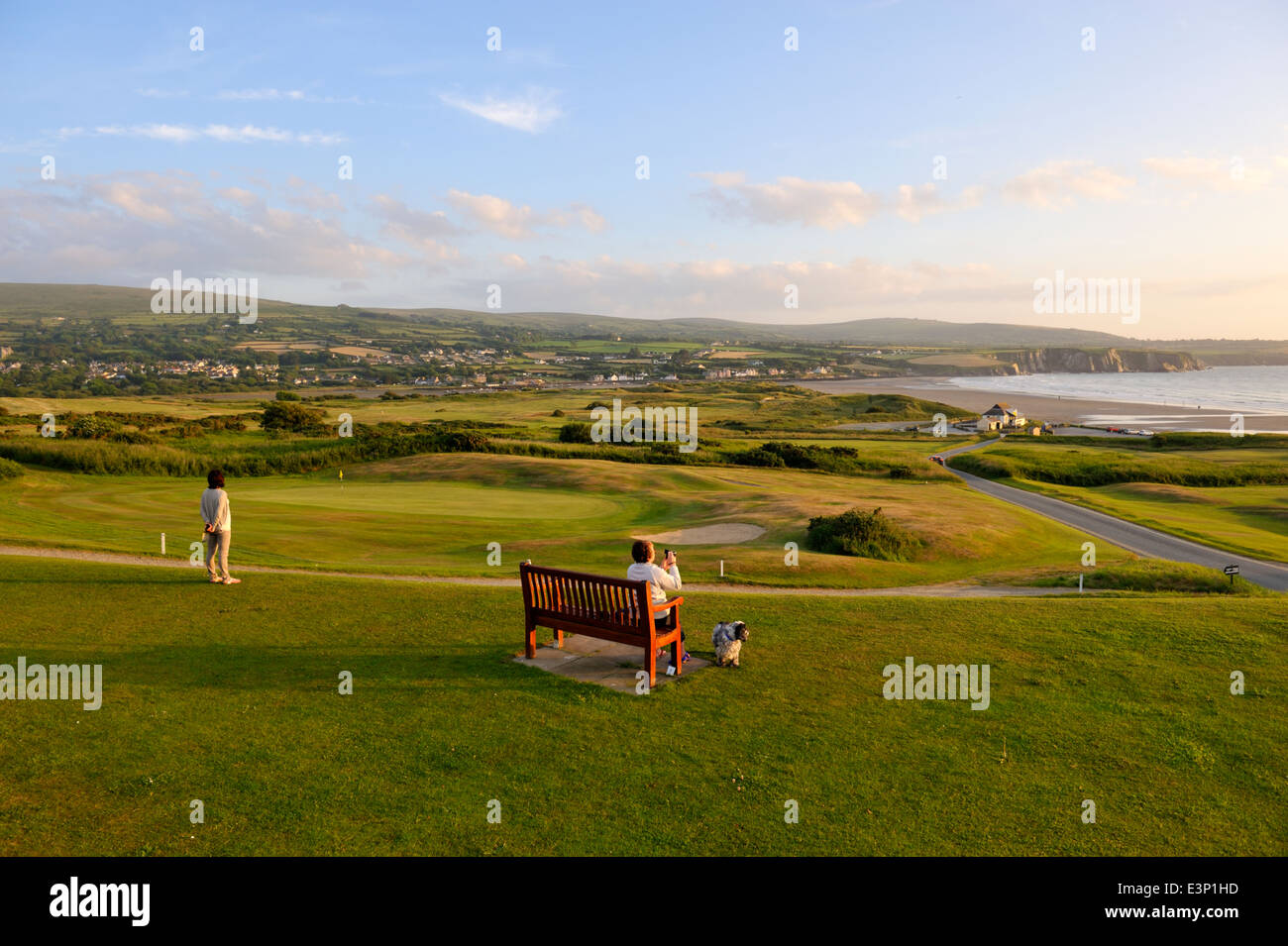 Newport Links Golf Club, donna su banco affacciato sulla spiaggia di Newport Pembrokeshire, Wales, Regno Unito Foto Stock