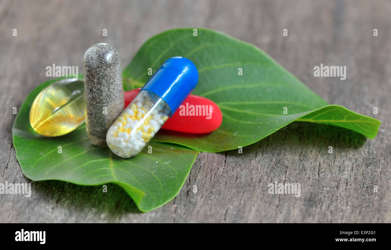Le pillole naturali su foglie verdi Foto Stock