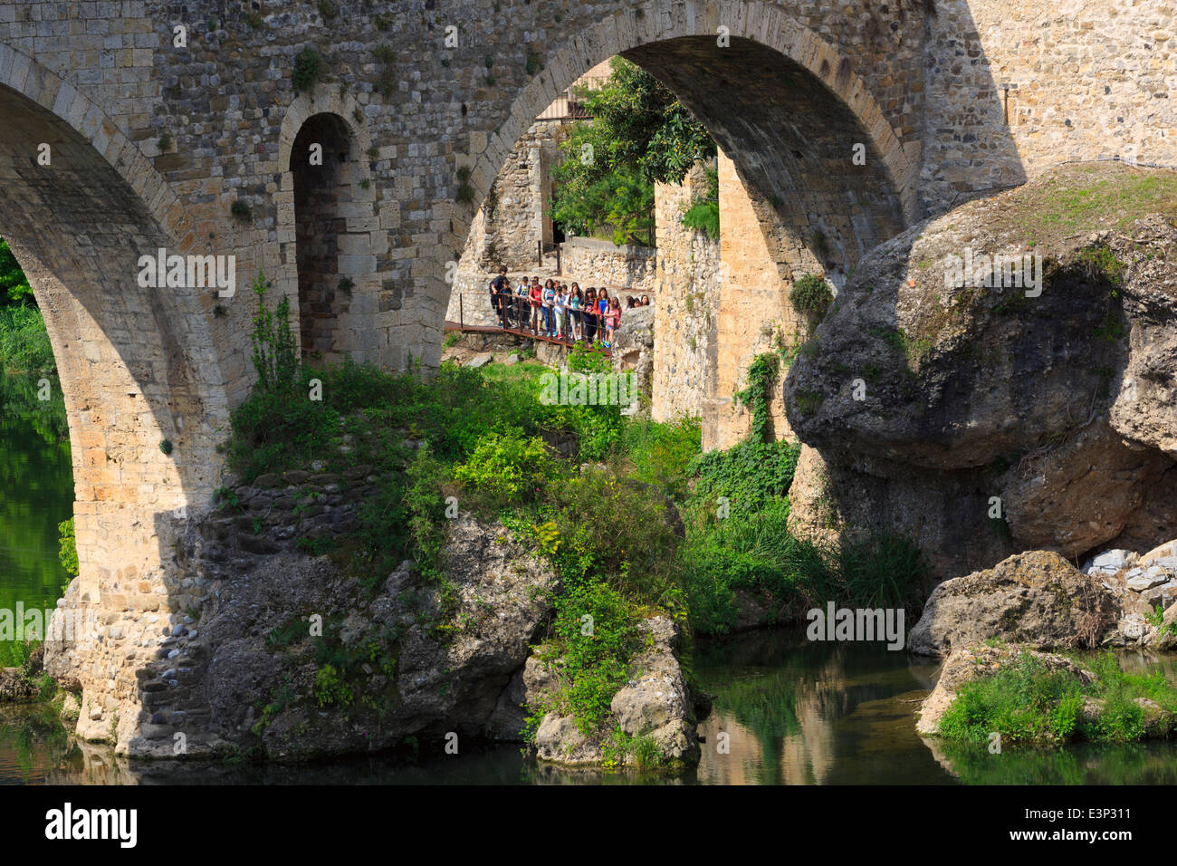 Besalu, Catalogna, Spagna. Un gruppo di scolari durante una gita guardare fino alla costruzione del ponte romanico. Foto Stock
