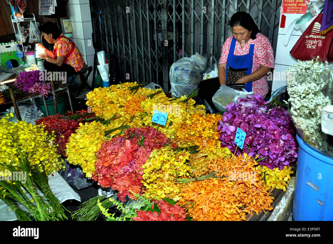 BANGKOK, Thailandia: Donna presso la sua bancarella vendendo multi-colore di orchidee a Bangkok il mercato dei fiori Foto Stock