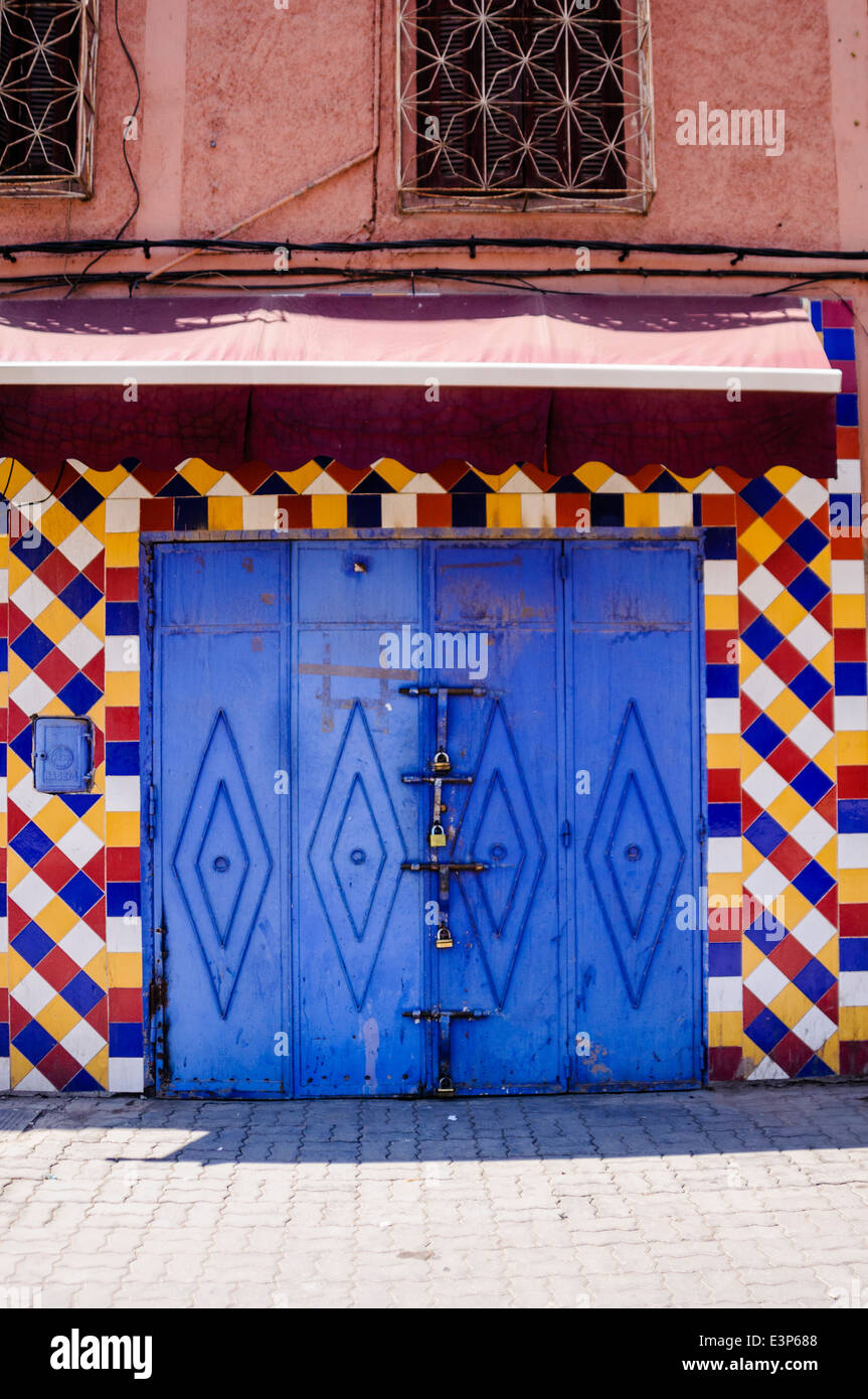 Blue porta di garage circondato da multi colorate piastrelle di ceramica su un edificio di Marrakech, Marocco Foto Stock