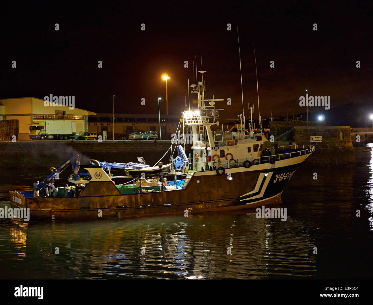 Getaria, Gipuzkoa, Paesi Baschi, Spagna. La trafficata commerciale porto di pesca. Un peschereccio si prepara a lasciare il porto di notte. Foto Stock