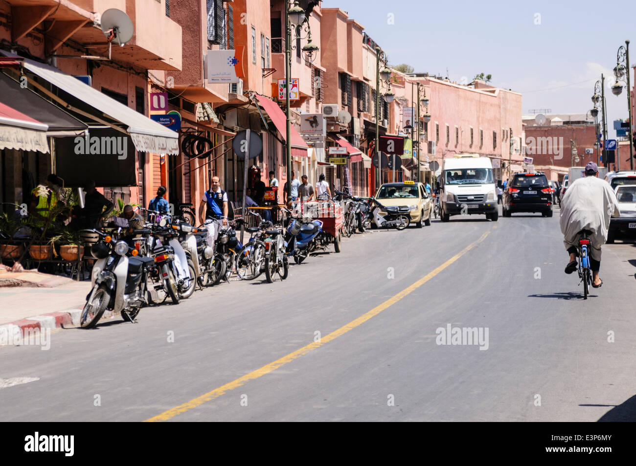 Strada tipica di Marrakech Marocco con parcheggiato scooter auto e furgoni. Foto Stock