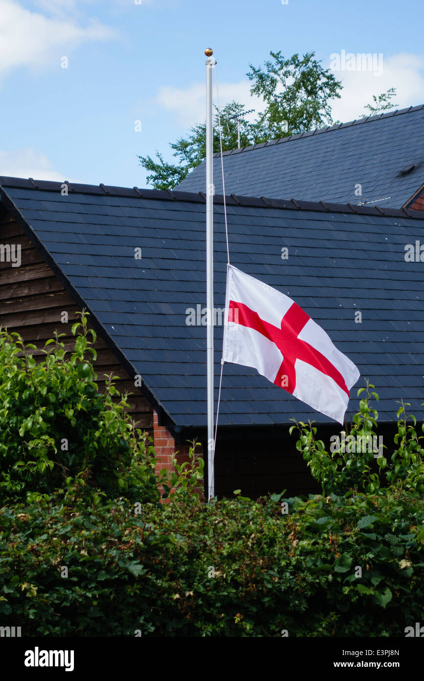 Una bandiera inglese (il St George's Cross) vola a metà del montante in Inghilterra dopo la sconfitta nel 2014 Coppa del Mondo di Calcio Foto Stock