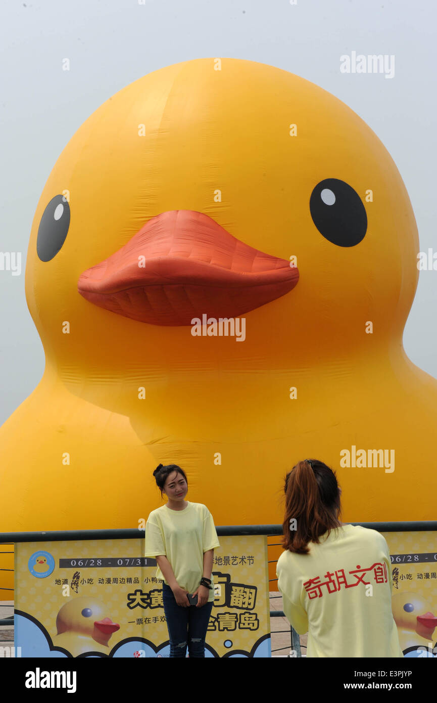 Qingdao, Cina Shandong. Il 27 giugno, 2014. Una giovane donna pone per le foto di fronte a un gigante Rubber Duck, il frutto dell'artista olandese Florentijn Hofman, a Qingdao Olympic Sailing Center a Qingdao, Cina orientale della provincia di Shandong, 27 giugno 2014. Un festival di arte a tema il rubber duck aprirà qui il sabato. Credito: Li Ziheng/Xinhua/Alamy Live News Foto Stock