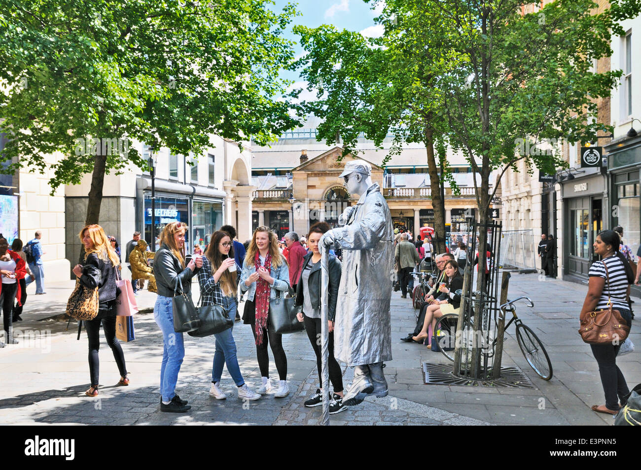 Statua umana suscita la curiosità di un gruppo di ragazze adolescenti in Covent Garden di Londra, Inghilterra, Regno Unito Foto Stock