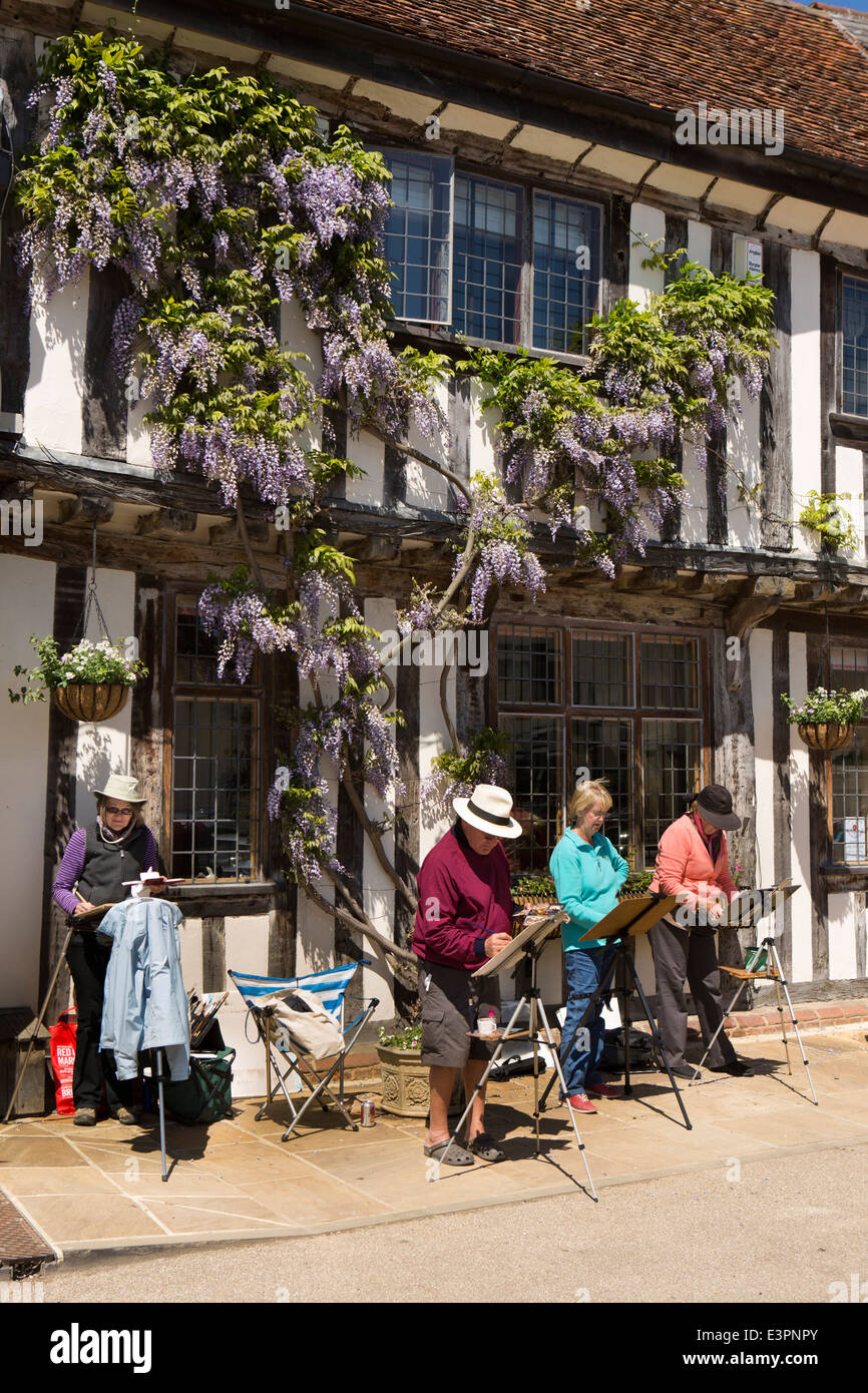Regno Unito Inghilterra, Suffolk, Lavenham, la piazza del mercato, degli artisti dilettanti pittura esterno sotto il glicine in fiore Foto Stock