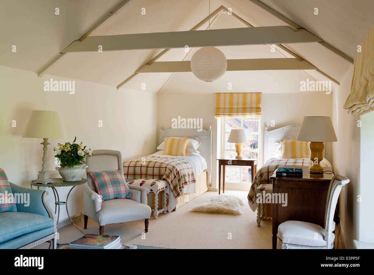 Mansarda Camera da letto doppia con soffitto con travi a vista, giallo listati matching tende e cuscini e poltrone di colore blu Foto Stock