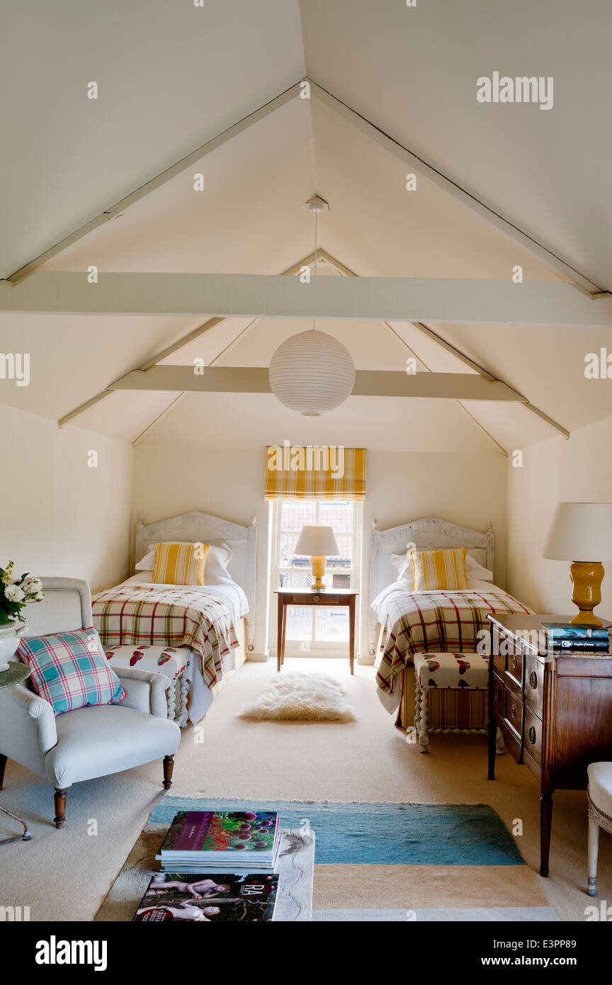 Mansarda Camera da letto doppia con soffitto con travi a vista, giallo listati matching tende e cuscini e poltrone di colore blu Foto Stock