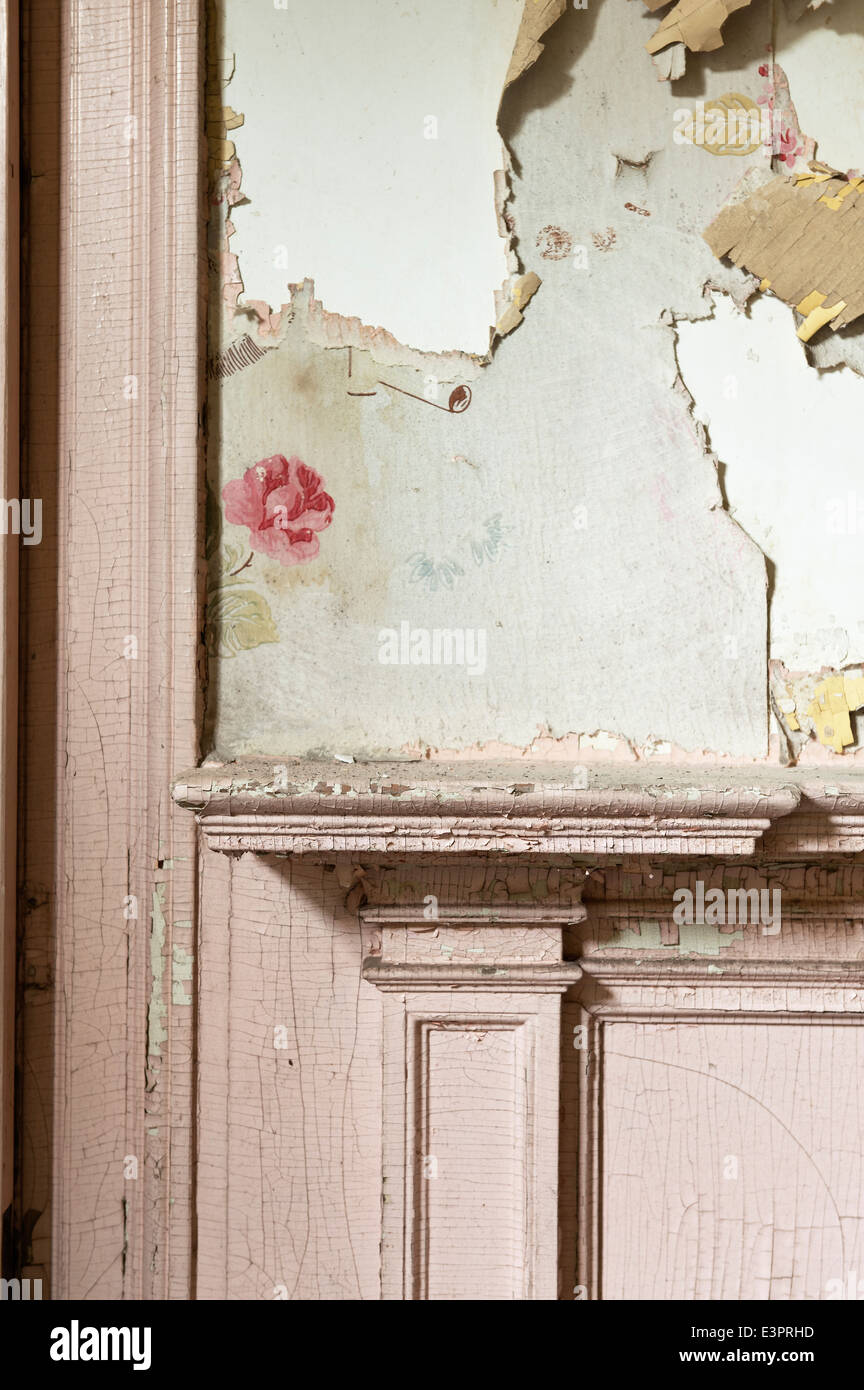 Dettagli della pelatura carta da parati floreale sopra mantelpiece con vernice incrinato Foto Stock