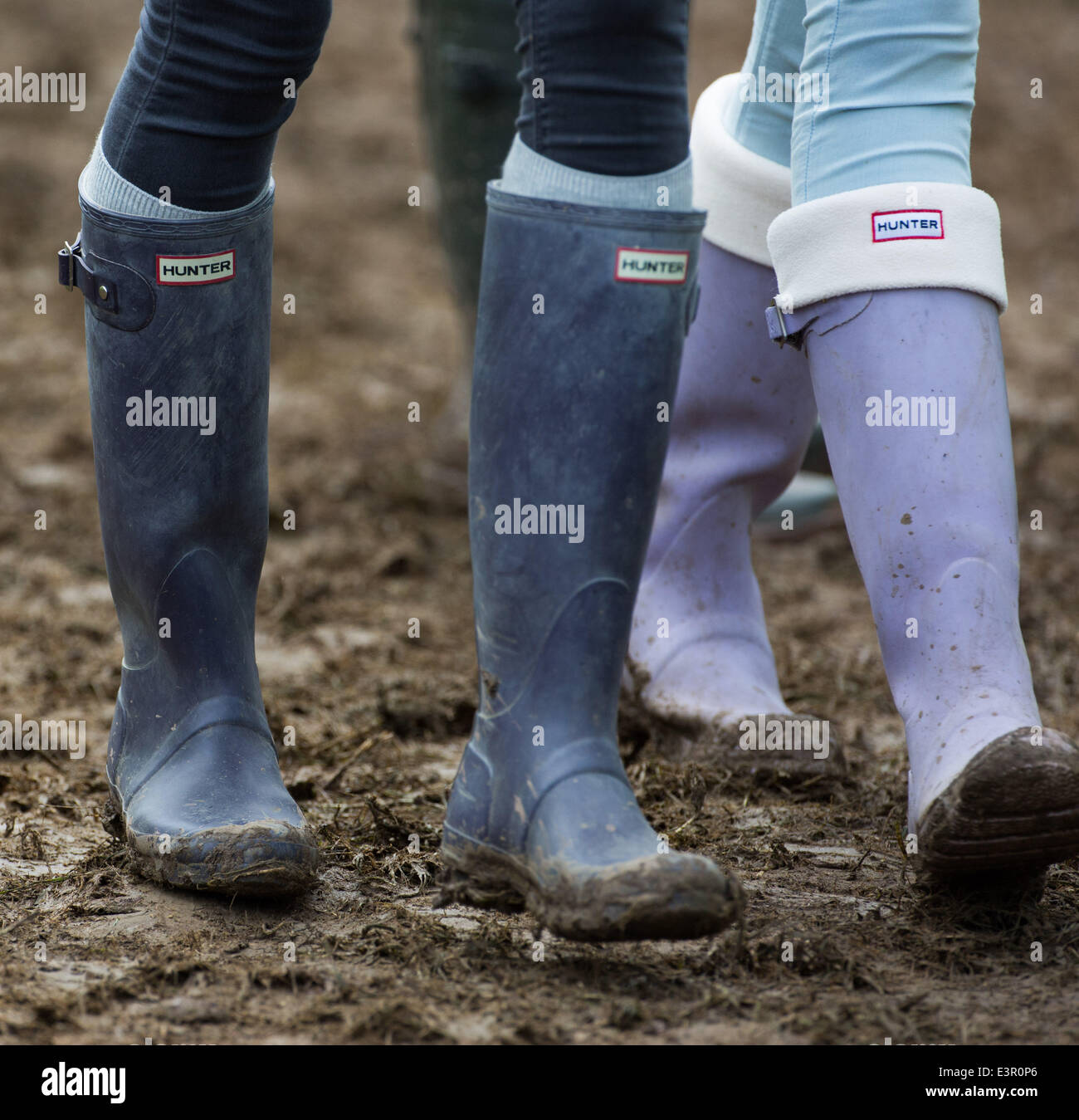 Stivali in gomma sono visti a piedi attraverso i campi fangosi di azienda agricola degna durante il 2014 Festival di Glastonbury nel Somerset, Giugno 2014. Foto Stock