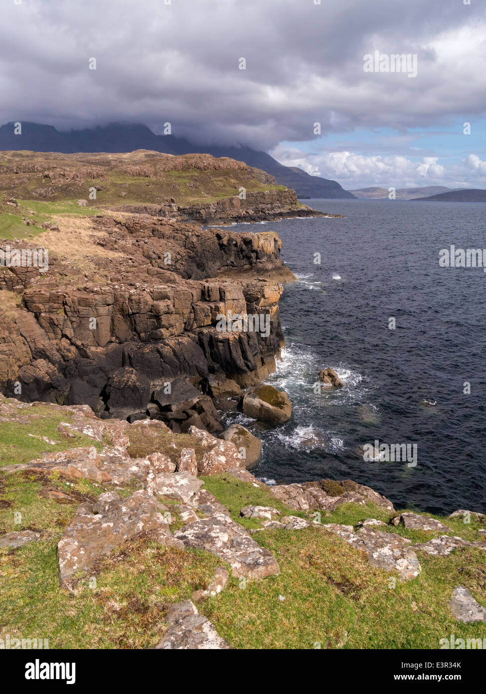 Rocciose scogliere del mare lungo il litorale del suono di Soay a Rubha un Dunain con Nero montagne Cuillin oltre, Skye, Scotland, Regno Unito Foto Stock