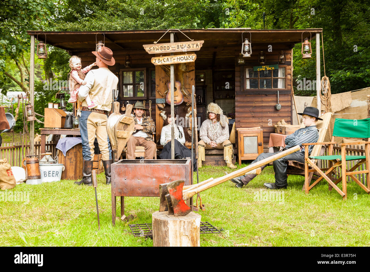 Leek, Staffordshire, Inghilterra. Il 22 giugno 2014, un weekend occidentale. Una famiglia vestita come U S i cowboys, al di fuori di simulazione di casa cat cabina. Foto Stock