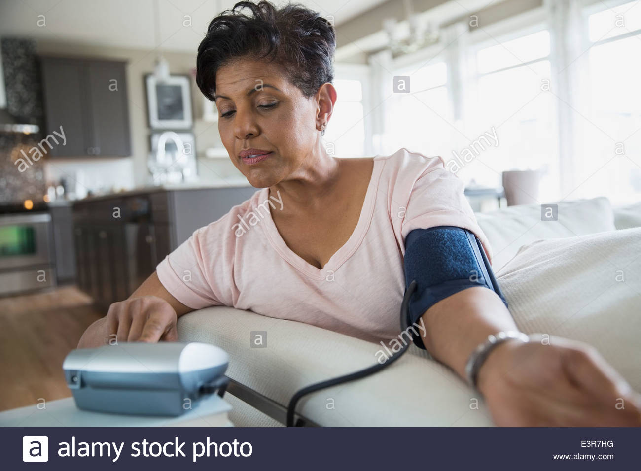 Donna controllando la pressione del sangue in salotto Foto Stock