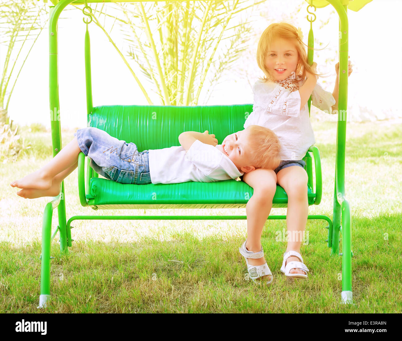 Due adorabili bambini trascorrere il tempo libero su swing, divertendosi in Summer Camp, vacanze attive, di felicità e di amicizia concetto Foto Stock