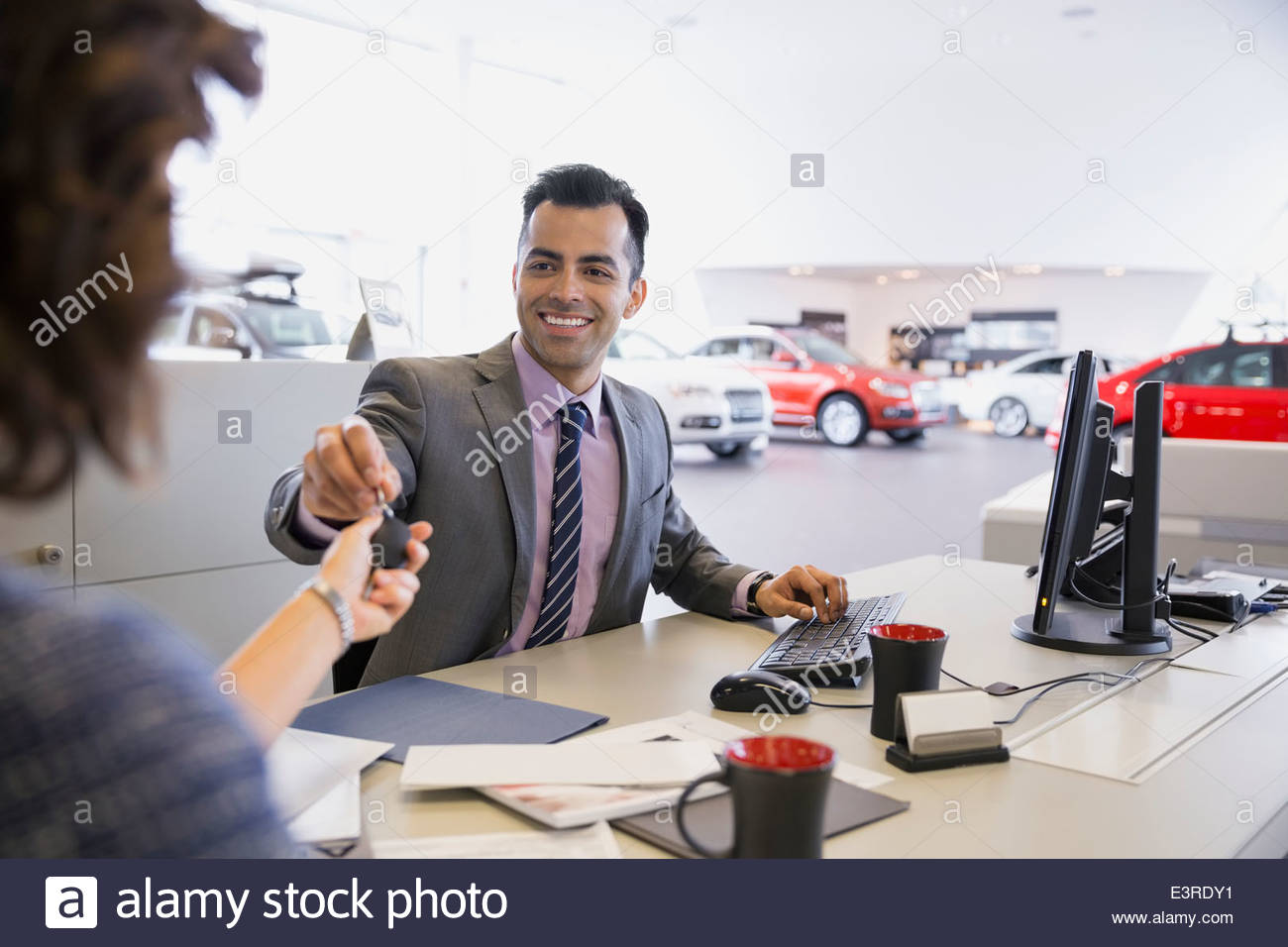 Venditore di dare le chiavi per donna in concessionaria auto Foto Stock