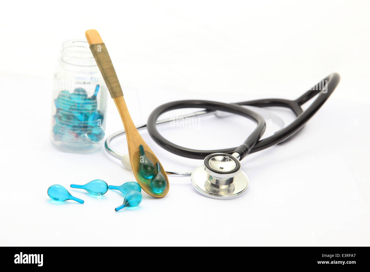 Vitamina versare dal cucchiaio di legno e uno stetoscopio su sfondo bianco Foto Stock
