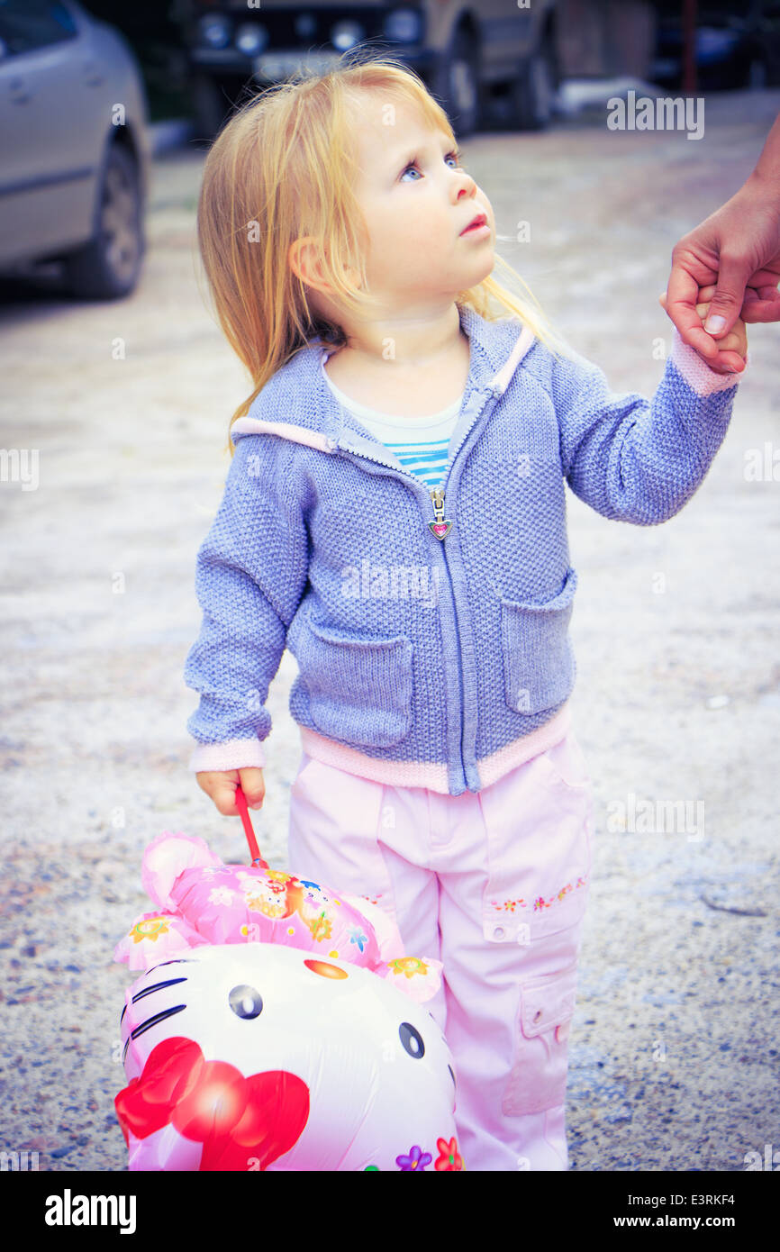 Bambina tenendo un giocattolo, tenendo la mano degli adulti e la ricerca di Foto Stock