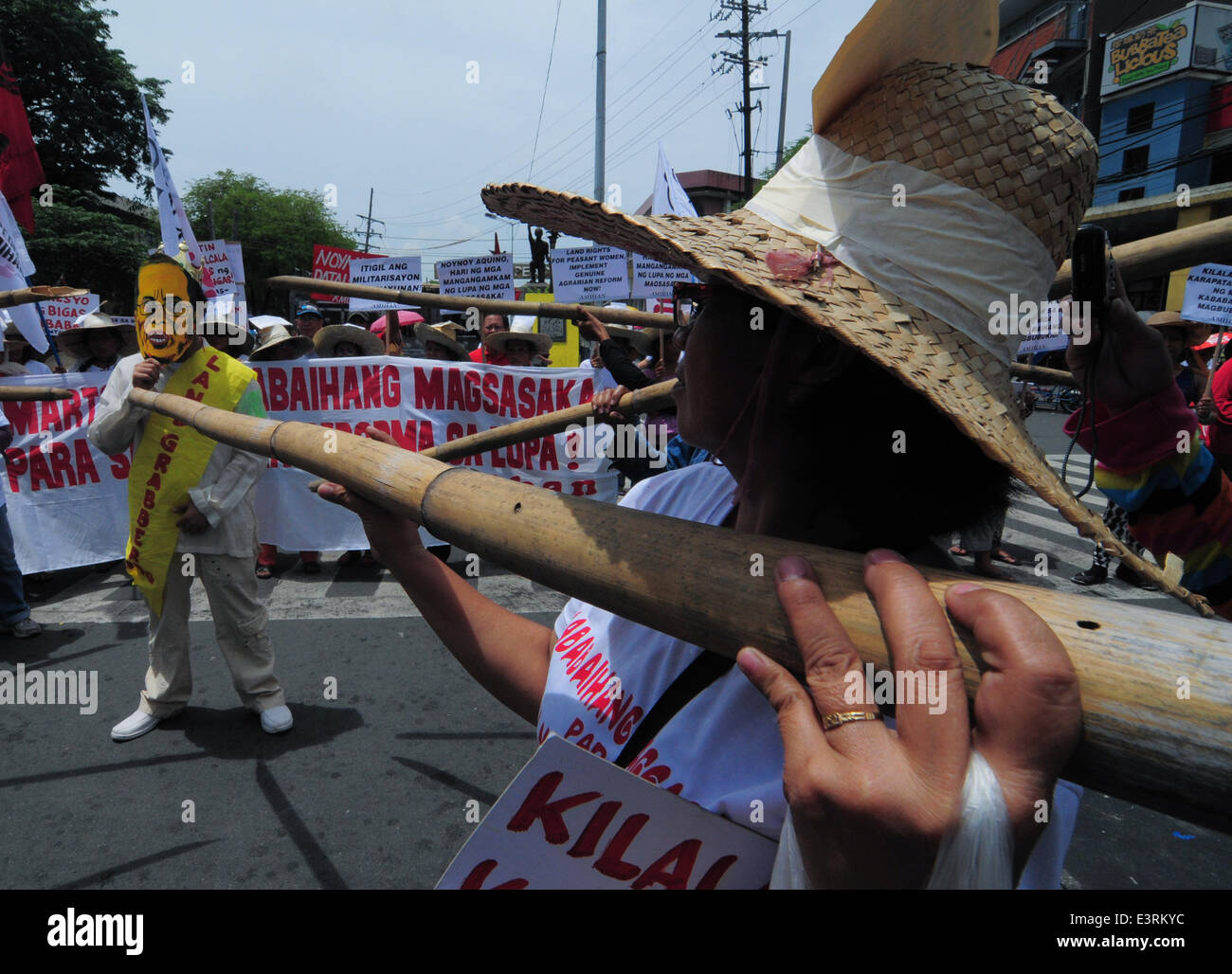 Manila, Filippine. Il 27 giugno, 2014. MANILA, Filippine - i dimostranti mockingly spinta germogli di bambù per un uomo che indossa il presidente filippino Aquino la maschera come agricoltori a partire dalla controversa zucchero station wagon Hacienda Luisita, come pure i manifestanti da differenti militante e gruppi di lavoro fase simultaneamente una protesta presso lo storico ponte Mendiola appena fuori dalle porte del Palazzo Presidenziale a Manila il 27 giugno 2014. Credito: ZUMA Press, Inc./Alamy Live News Foto Stock