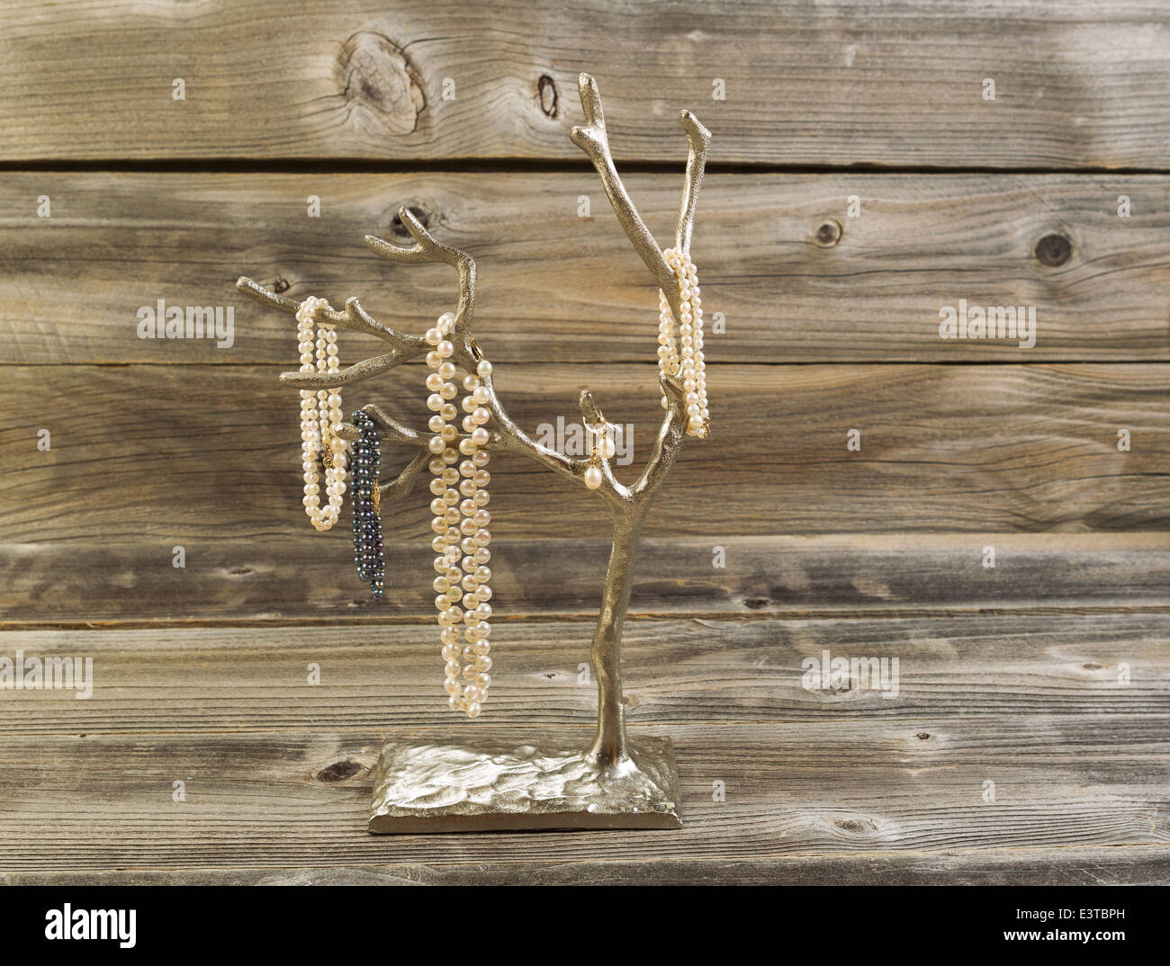 Vista frontale immagine di perle naturali su metallo cromato con struttura in legno rustico in background Foto Stock