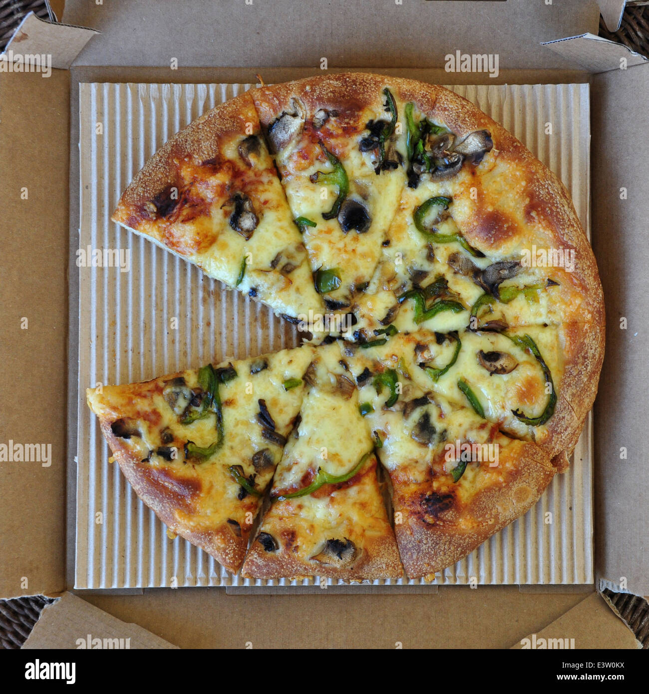 Pizza da asporto con funghi e pepe verde in scatola di cartone. Italian fast food sfondo. Foto Stock